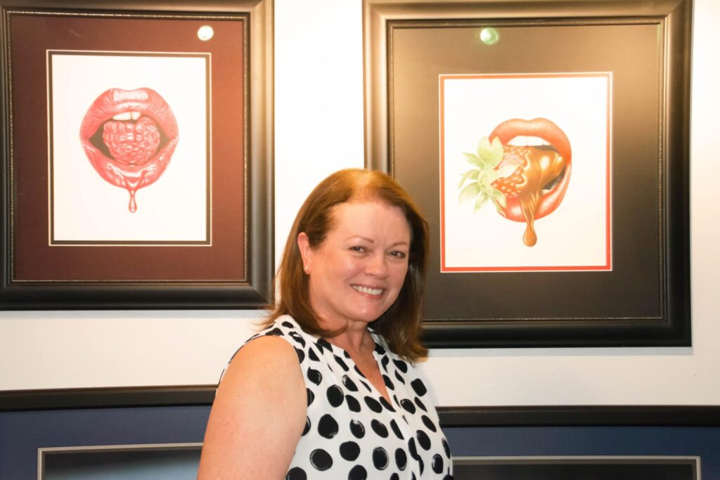 Janet Waltz standing in front of two of her paintings